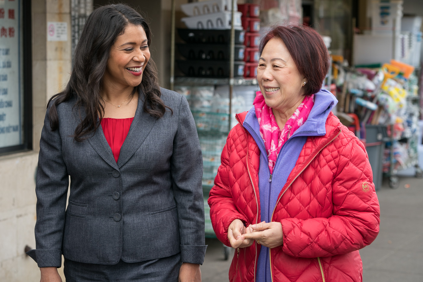 Mayor London Breed walking with woman who is wearing a red jacket